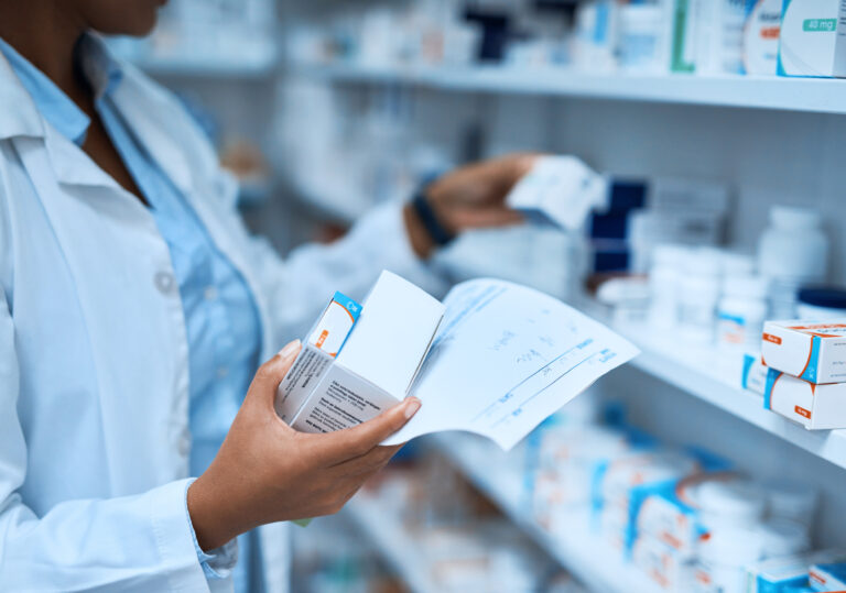 Pharmacist selecting medications from shelf.