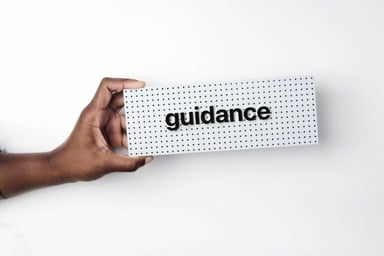 Hand holding a sign saying 'guidance.'