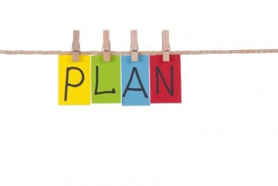 Letter spelling out 'Plan' are written on colored paper and hanging up on a clothesline.