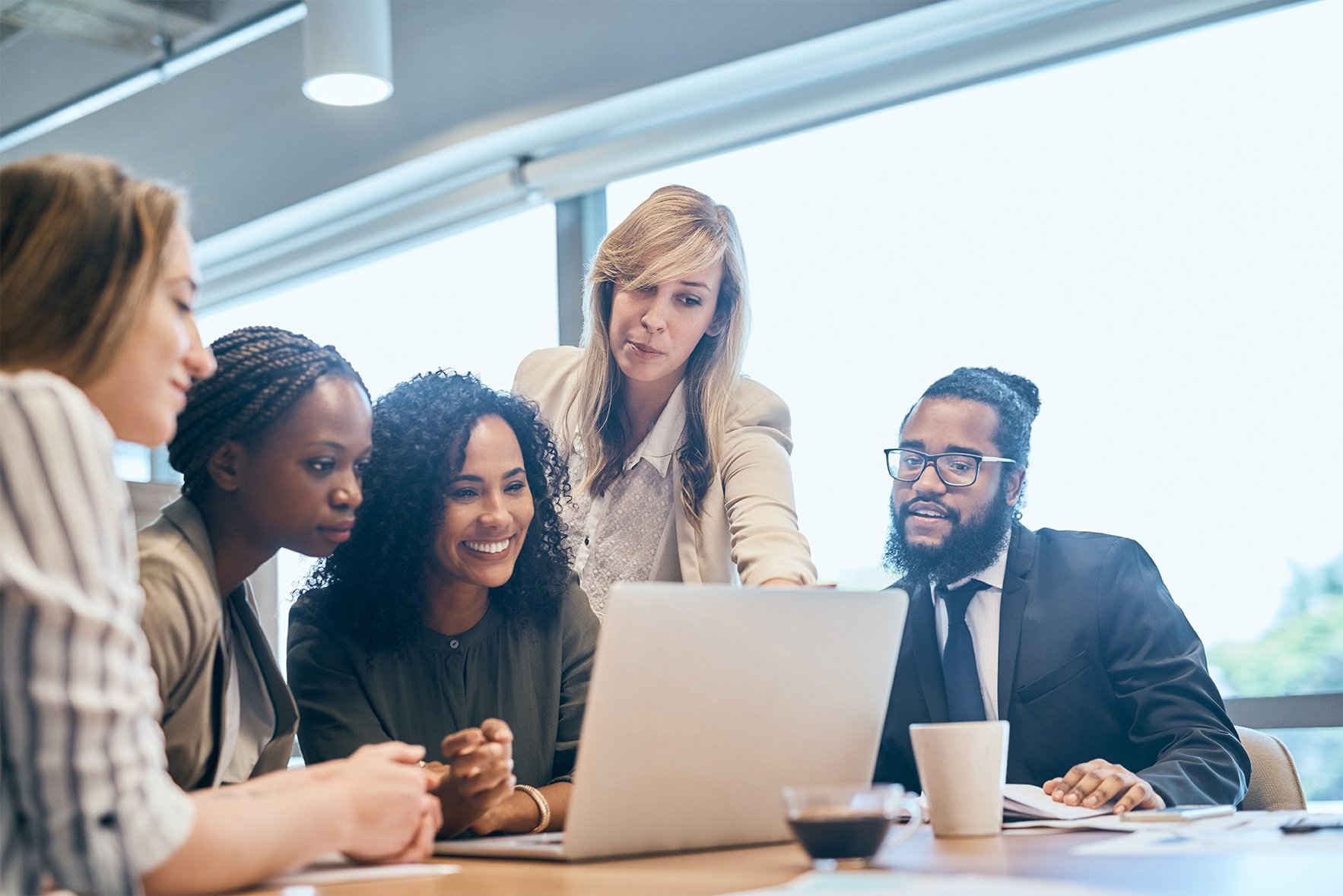 Woman pointing her coworkers to something on a laptop