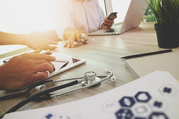 Healthcare workers sitting at table working on tablet devices