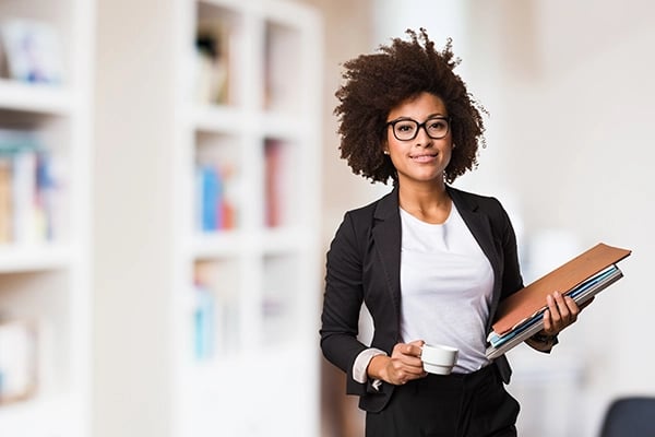 Professional woman holding stack of folders and small cup