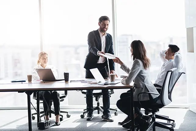 Man handing papers to a coworker at a business meeting