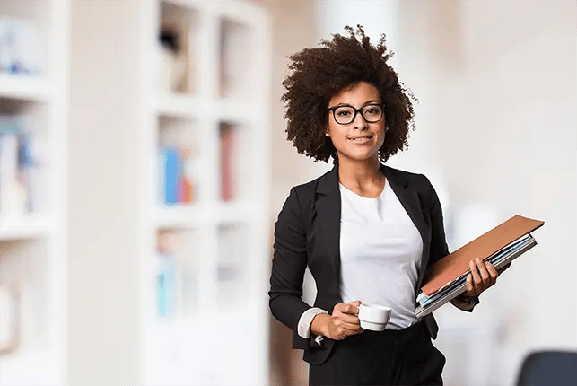 Woman wearing glasses and holding stack of papers and files and espresso cup