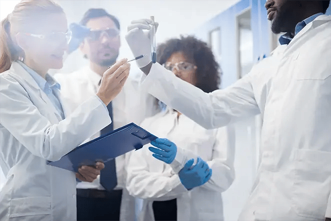 Group of healthcare professionals in lab-coats pointing to a test tube