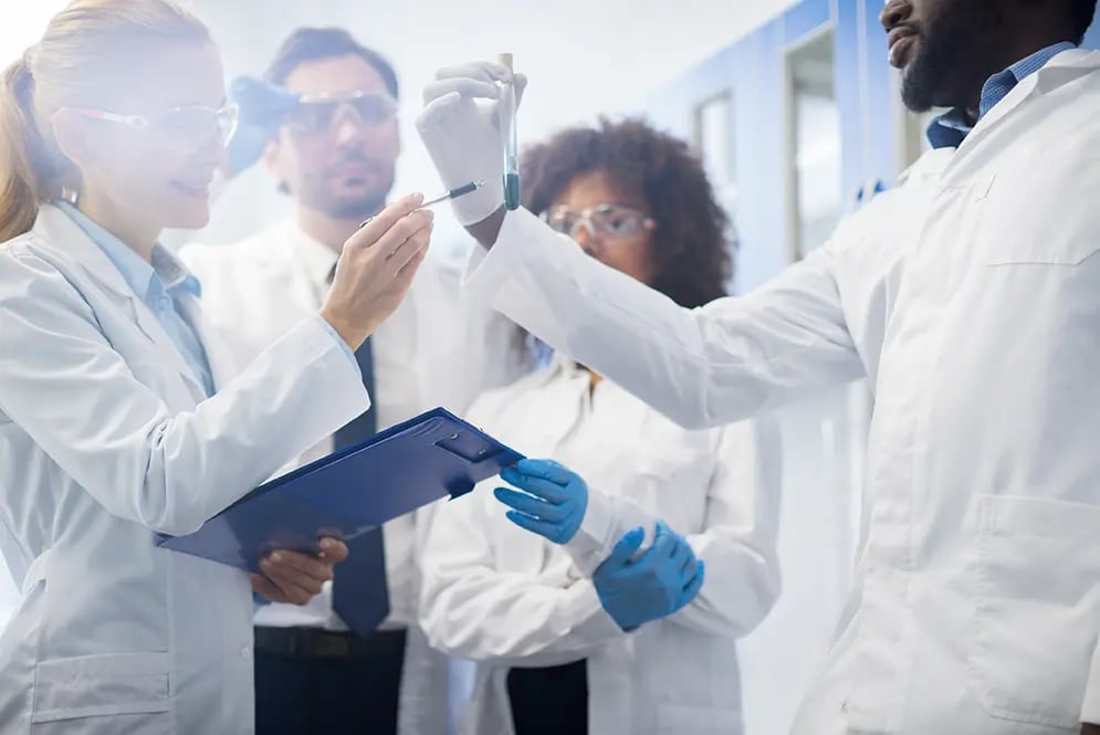 group-of-healthcare-professionals-in-labcoats-pointing-to-a-test-tube