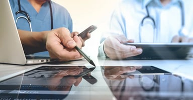 Healthcare providers pointing to a tablet device