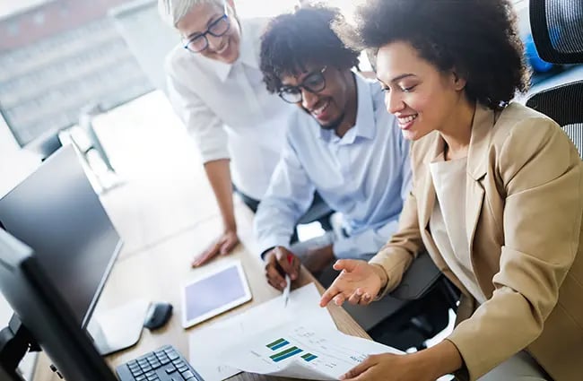 Business professionals smiling at a desk reviewing data