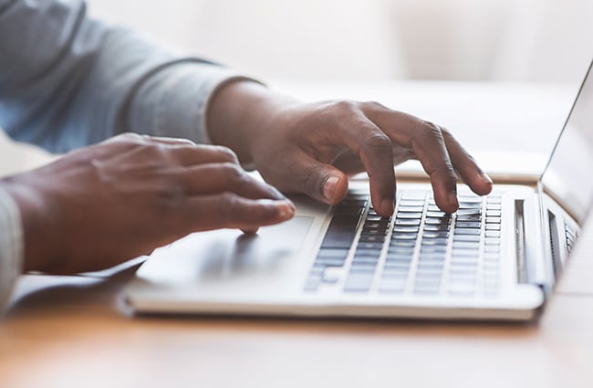 Hands typing on laptop