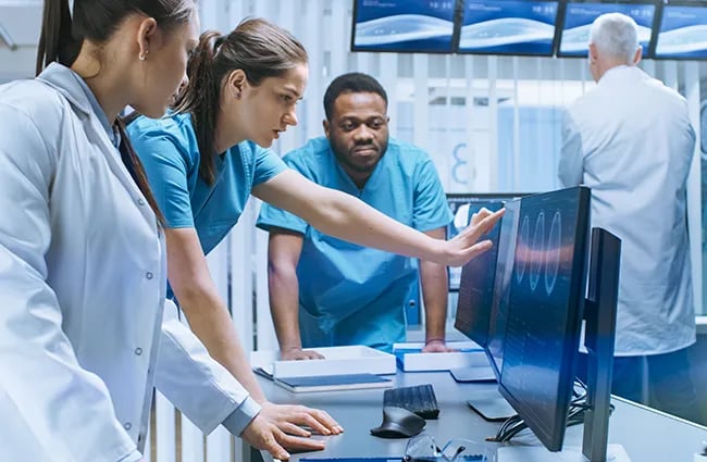Health care professionals reviewing computer monitors inside an examination room