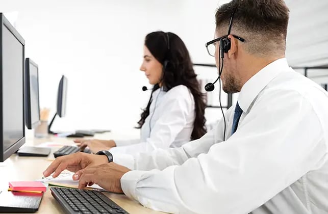 Customer service professional in a contact center wearing headset asking a coworker-a-question