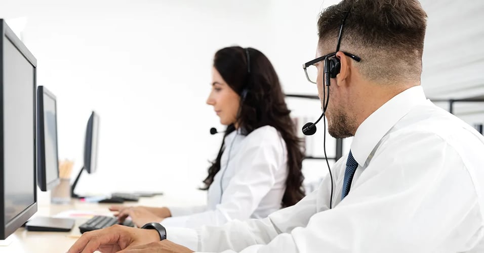 Customer service professional wearing headset asking coworker a question