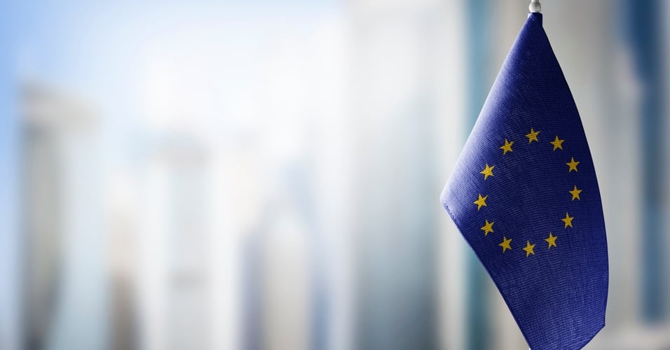 European Union flag on a small desk flagpole with a blurred background.