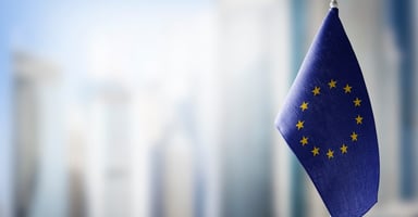 European Union flag on a small desk flagpole with a blurred background.