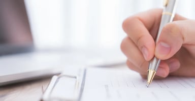 Hand writing on clipboard with a pen