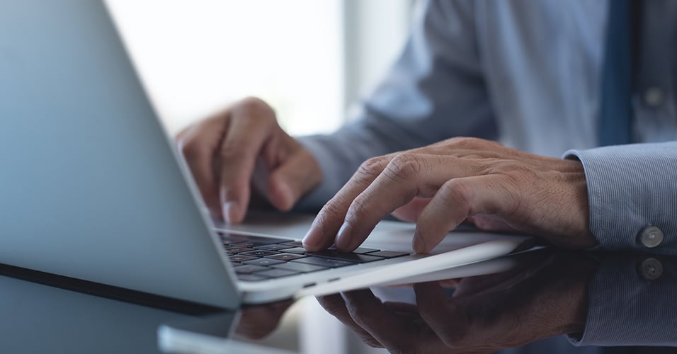 Hands typing on laptop