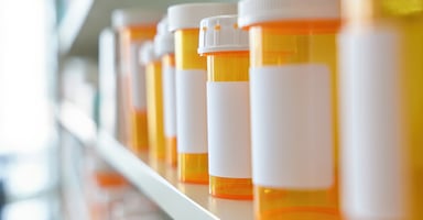Prescriptions bottles lined neatly on a pharmacy shelf with clear label edges 