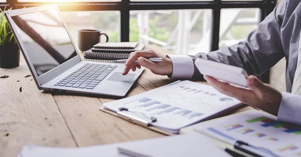Man working with laptop, mobile phone, and worksheets
