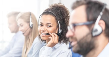 Row of customer service professionals wearing headset one person smiling at camera