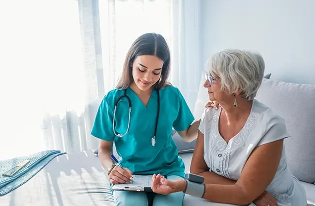 Healthcare provider writing on clipboard while attending to a patient