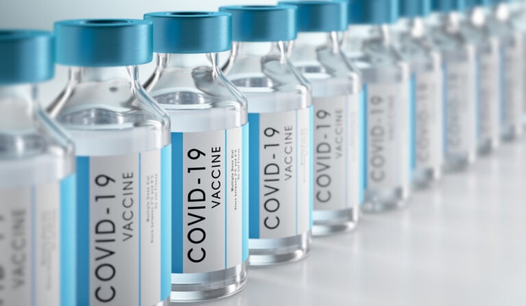 Several COVID-19 vaccine vials lined up on a table.