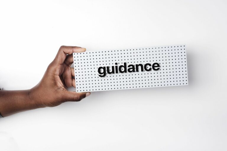 Hand holding a sign saying 'guidance.'