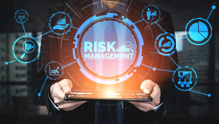 'Risk management' is illuminated by light emitting from a tablet device.