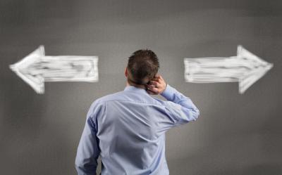 Man looking at two arrows pointing in opposite direction.