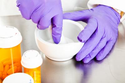 Gloved hands creating a compounded drug in a bowl.