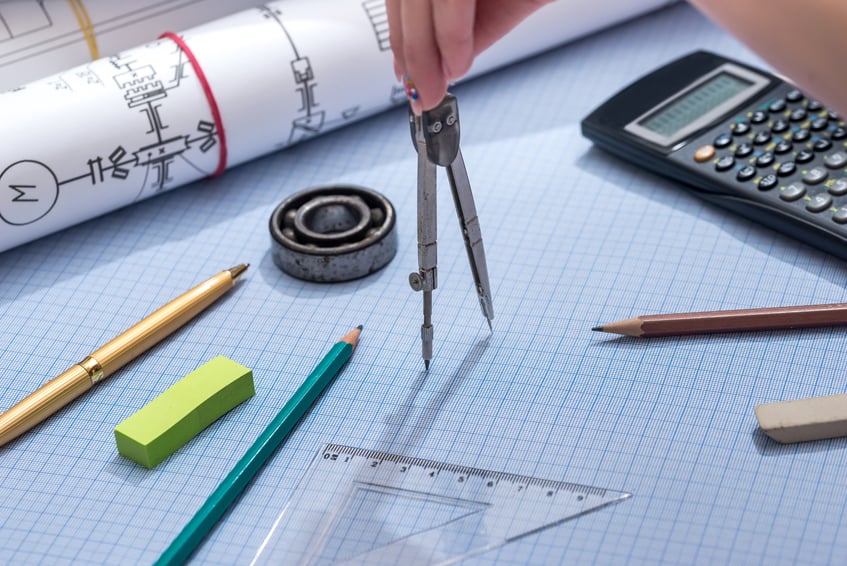 A hand holding a compass ruleron a graph paper