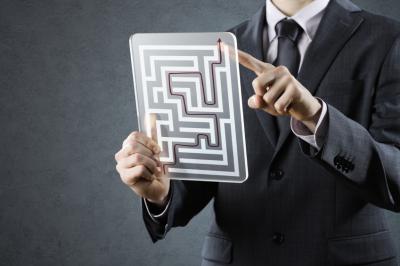 Man in a suit wodling up a transparent tablet with a maze.