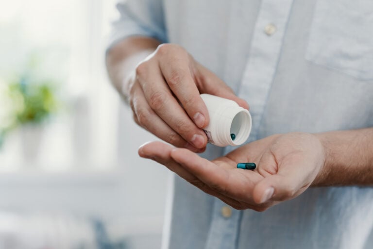 Healthcare patient pouring a pill out of a medicine bottle.