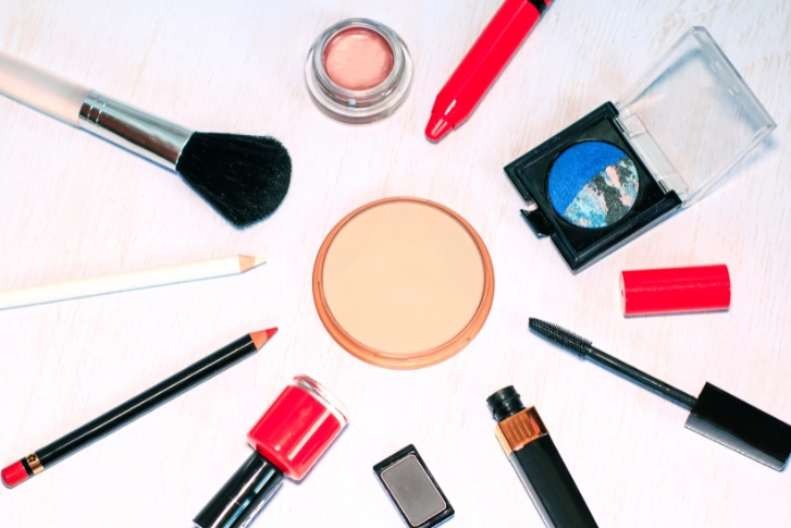 Cosmetic products laid out in a circle with a make up powder compact in the middle.