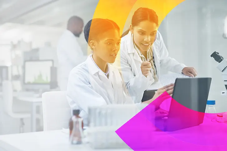 Two women collaborating in a laboratory working on a laptop computer.