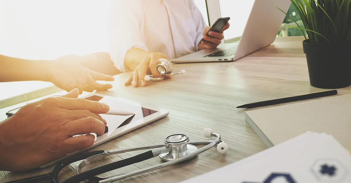 People working at a table with medical and computer devices