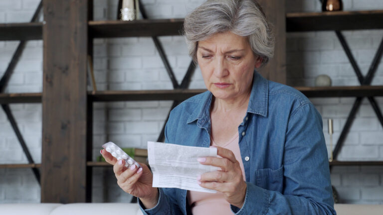 A woman holding instructions an a packet of pills.